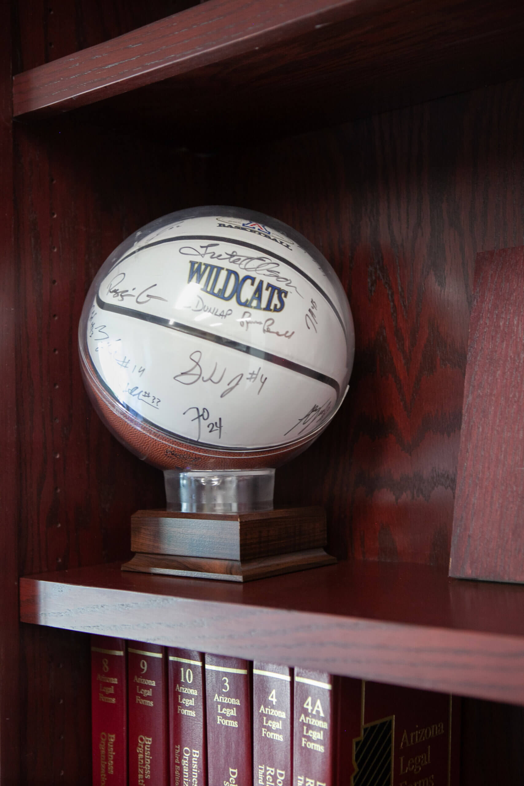A signed basketball on a shelf above law books