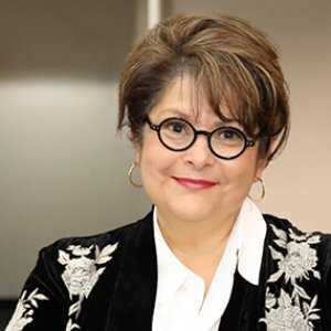 Brown haired female lawyer with dark-framed glasses and a black blouse